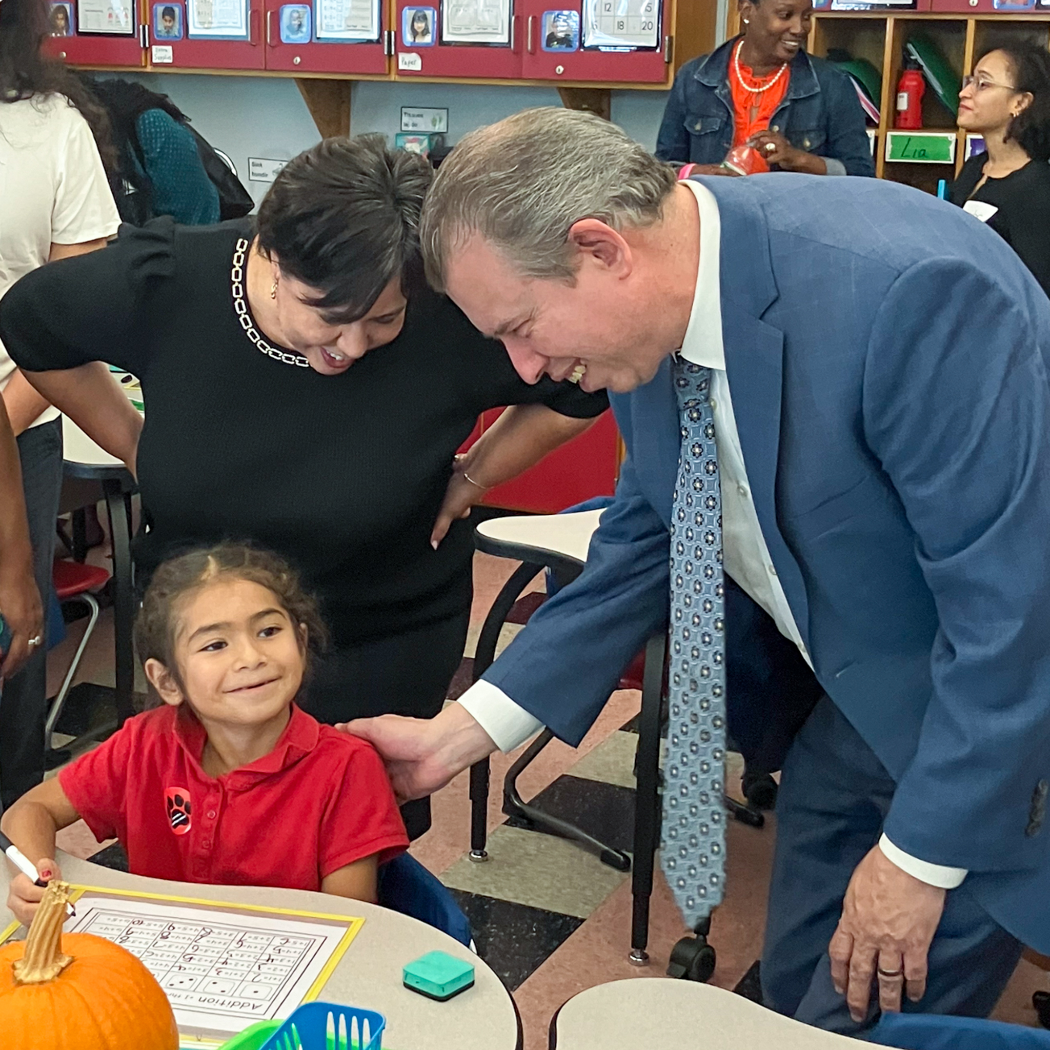 Superintendent Almi G. Abeyta and DESE Commissioner Pedro Martinez speaking with a smiling student sitting at a school desk.