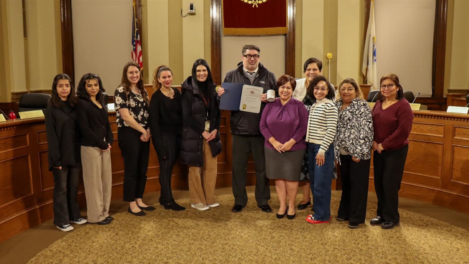 John Ruggiero photographed with a Name Strength and Story Award alongside the Chelsea School Committee