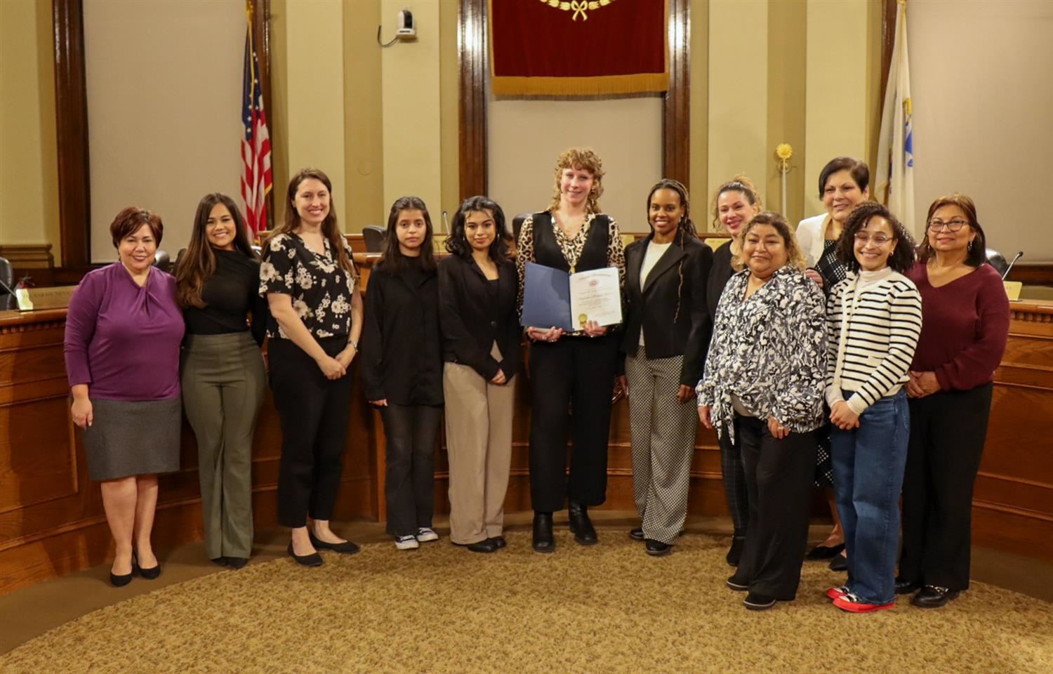 Morgan Grace photographed with a Name Strength and Story Award alongside the Chelsea School Committee