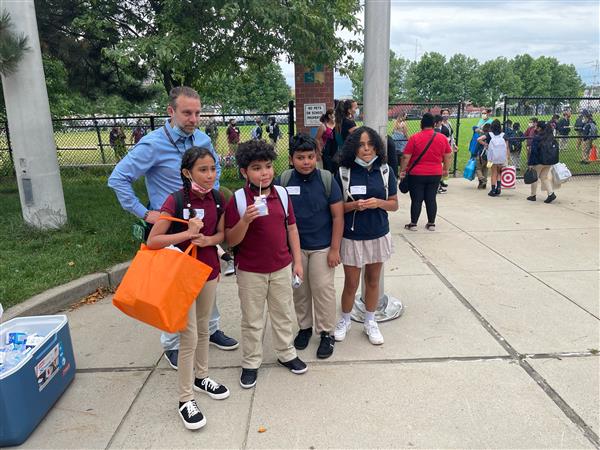 Students posed with Coordinator of Extended Learning Malik Howshan outside the Mary C. Burke Elementary Complex. 